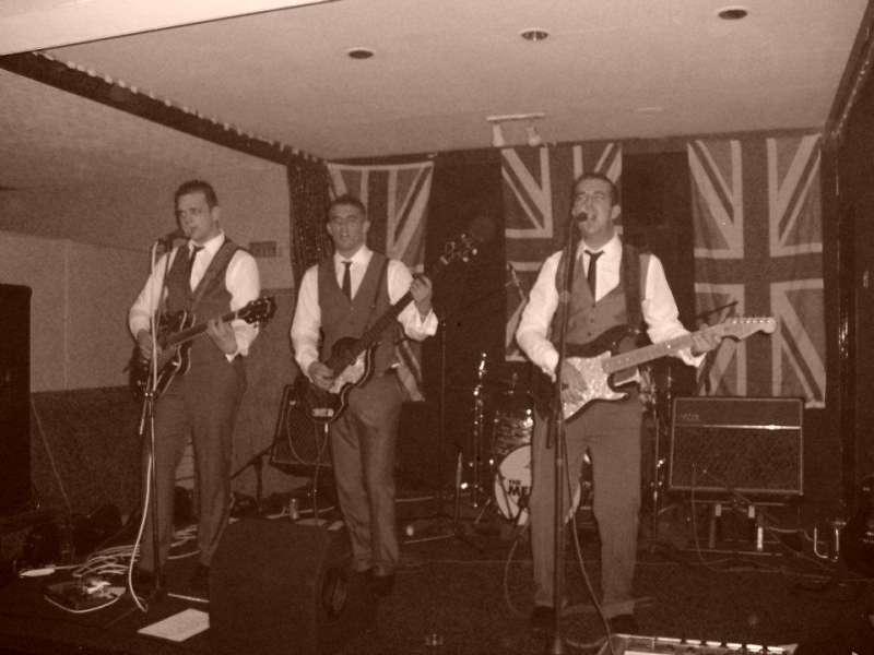 The mercy Band playing on stage with union Jack flags behind them